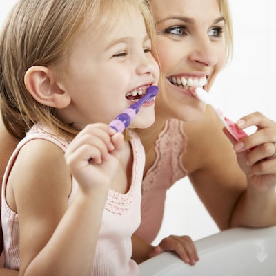 Little girl and her mum brushing their teeth and smiling