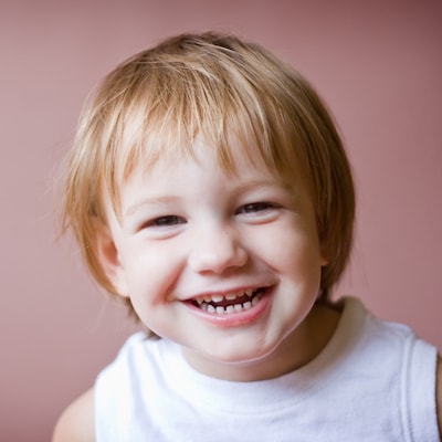 Little girl smiling in front of a pink background