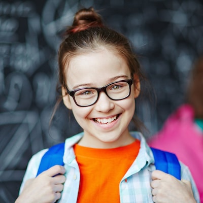 Older girl wearing glasses and a backpack while smiling