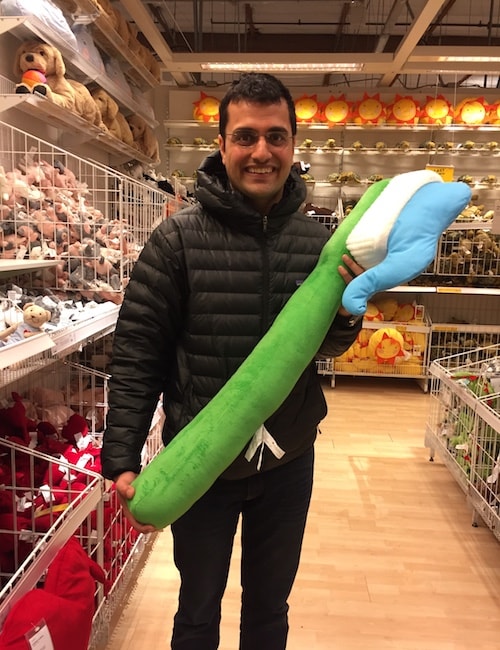 Dr. Ketan Jumani holding a giant toothbrush and smiling in a toy store