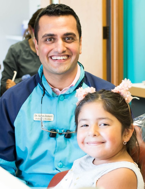 Dr. Ketan Jumani smiling in his uniform with a young female patient