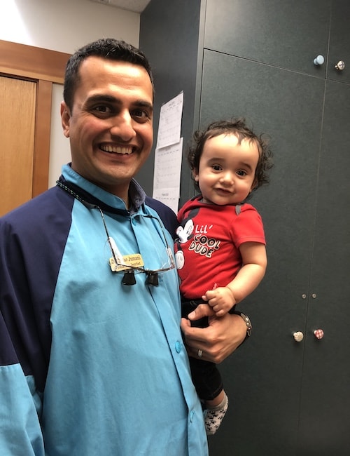 Dr. Ketan Jumani smiling and holding a baby in our office