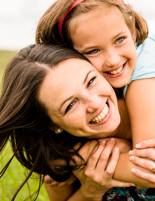 Daughter getting a piggyback from her mother as they are both laughing