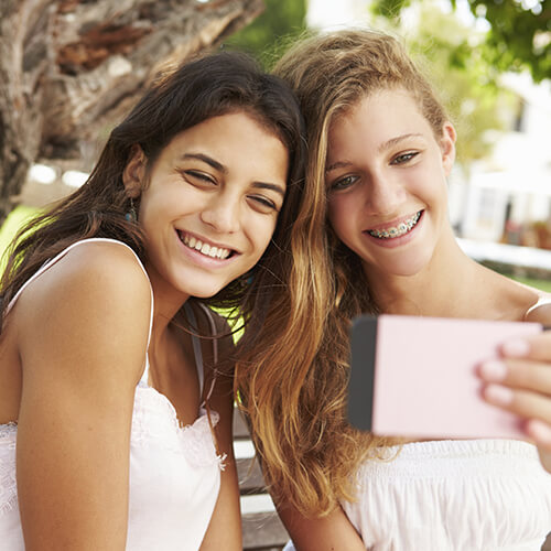 Image of two teenage girls taking a selfie outdoors