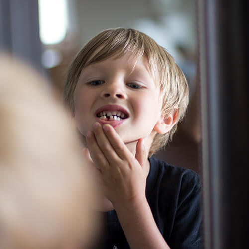 Little boy looking at his teeth in the mirror