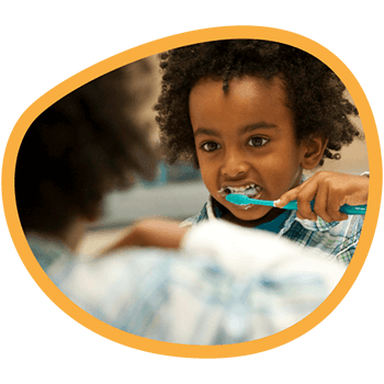 Kid brushing his teeth in front of a mirror